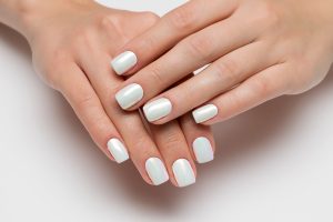 Wedding white pearl manicure on short square nails on a white ba